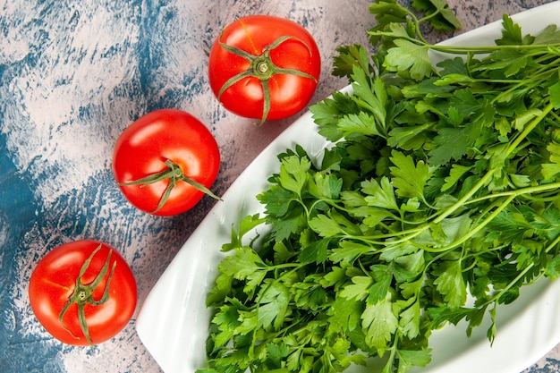 Vue de dessus des légumes verts frais avec des tomates sur fond bleu clair