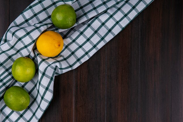 Vue de dessus des limes au citron sur une serviette à carreaux sur une surface en bois
