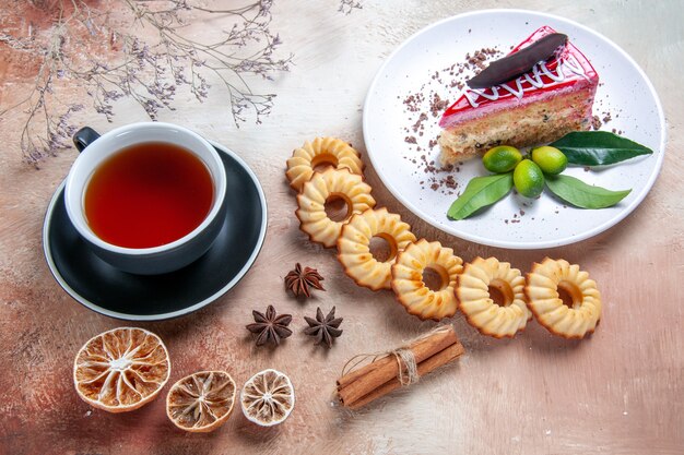 Vue de dessus de loin une assiette à gâteau d'un gâteau appétissant cookies une tasse de thé citron anis étoilé