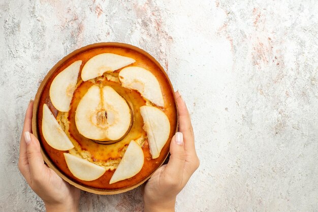 Vue de dessus de loin gâteau aux poires gâteau appétissant aux poires dans les mains sur fond blanc