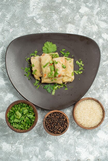 Vue de dessus de loin plat avec assiette d'herbes de chou farci et bols de riz papper noir et herbes au centre de la table