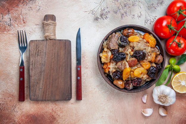 Vue de dessus de loin tomates pilaf citron ail bol de pilaf la fourchette couteau planche à découper