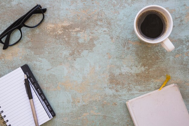 Vue de dessus des lunettes; bloc-notes en spirale; stylo et journal sur un vieux fond rustique