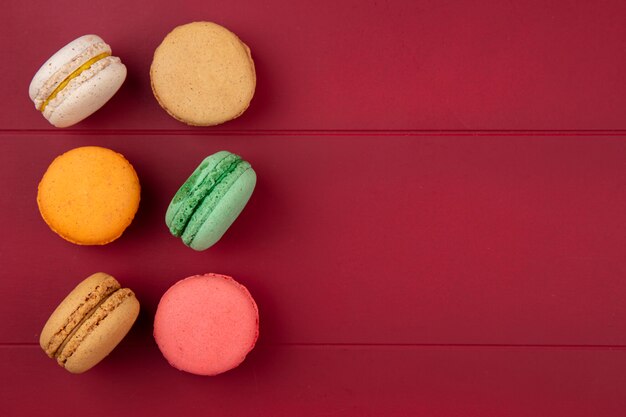 Vue de dessus des macarons colorés sur une surface rouge