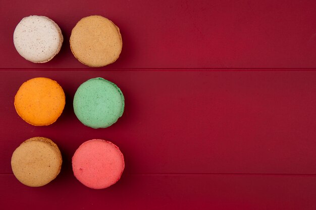 Vue de dessus des macarons colorés sur une surface rouge