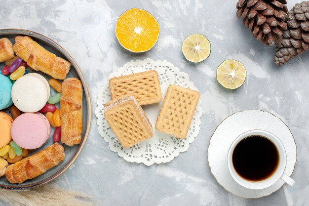 Vue de dessus macarons français avec bagels et tasse de thé sur blanc