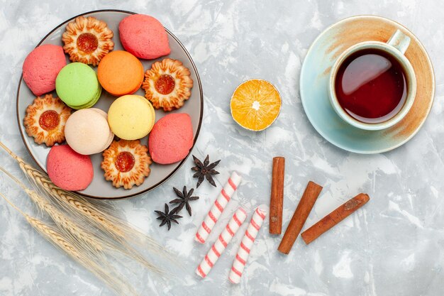 Vue de dessus des macarons français avec des biscuits à la cannelle et du thé sur une surface blanc clair