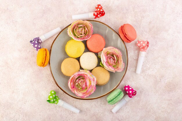 Une vue de dessus macarons français colorés sur le bureau rose biscuit gâteau au sucre sucré