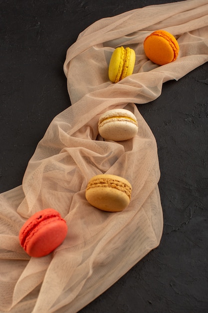 Photo gratuite une vue de dessus macarons français colorés délicieux et cuits au four sur la table noire biscuit gâteau biscuit sucre