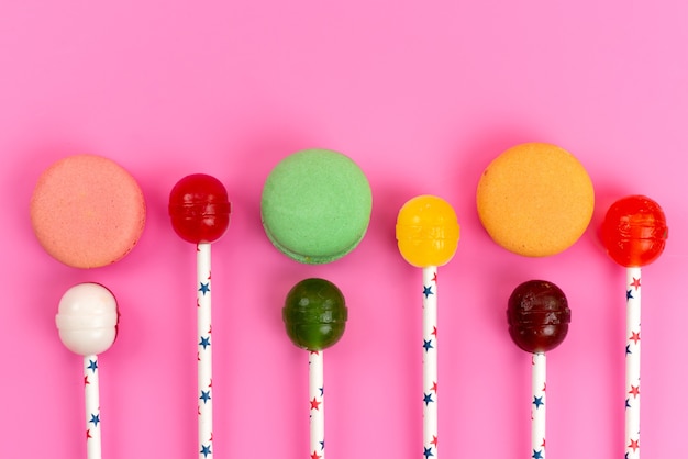 Une vue de dessus macarons français colorés avec des sucettes sur rose, gâteau au sucre sucré