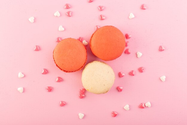 Une vue de dessus macarons français colorés sur la table rose gâteau biscuit sucre sucré