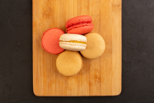 Une vue de dessus macarons français de couleur délicieux et délicieux sur le bureau en bois et table sombre