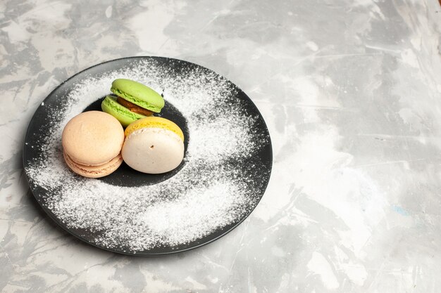 Vue de dessus macarons français délicieux gâteaux colorés à l'intérieur de la plaque sur la surface blanche légère gâteau biscuit tarte thé sucre biscuit sucré