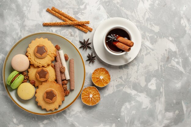 Vue de dessus macarons français avec des gâteaux et des biscuits sur la surface blanche biscuit biscuit sucre cuire gâteau tarte sucrée