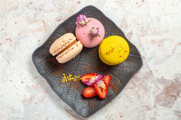 Vue de dessus des macarons français à l'intérieur de la plaque sur un gâteau sucré de biscuit de biscuit de table blanche