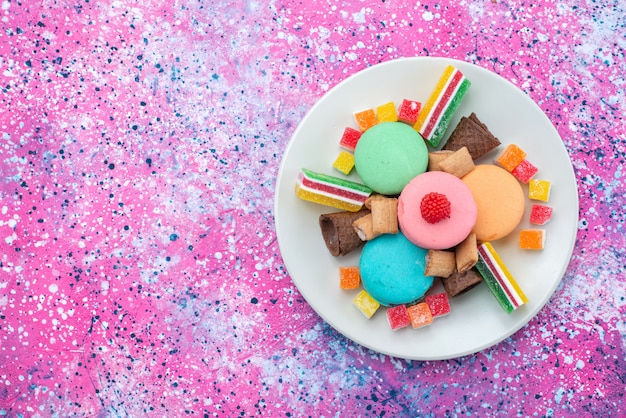 Photo gratuite vue de dessus macarons français à l'intérieur de la plaque avec des marmelades sur le gâteau de fond coloré couleur pâte sucrée sucre bsicuit