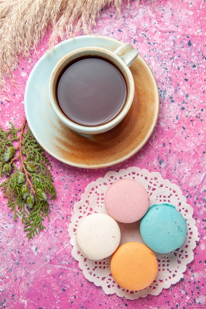 Vue de dessus des macarons français avec tasse de thé sur la surface rose