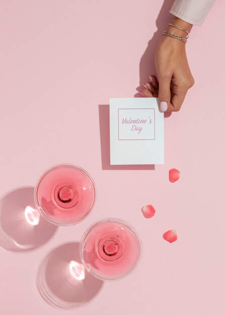 Vue de dessus de la main des femmes tenant la carte de la Saint-Valentin à côté de verres avec des boissons