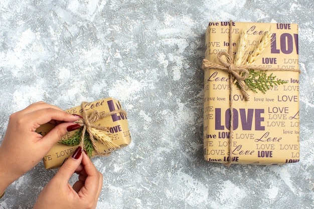 Photo gratuite vue de dessus de la main tenant l'un des beaux cadeaux de noël avec inscription d'amour sur la surface de la glace