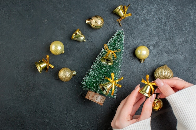 Vue de dessus de la main tenant les coffrets cadeaux accessoires de décoration et arbre de Noël sur fond sombre