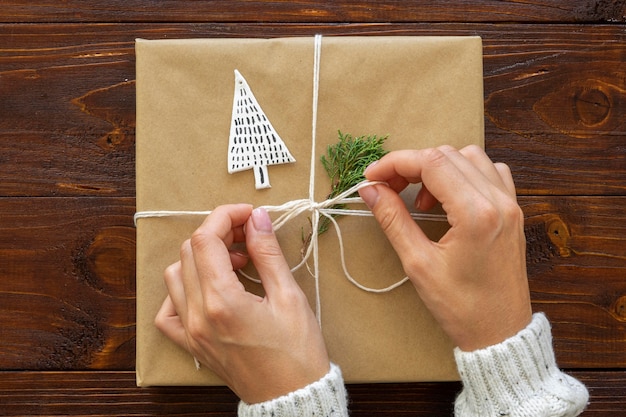 Vue de dessus des mains attachant le cadeau de Noël