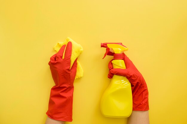 Vue de dessus les mains avec des gants en caoutchouc tenant des fournitures de nettoyage