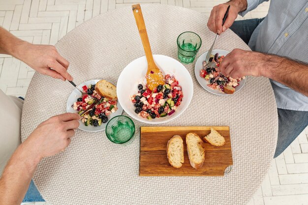 Vue de dessus des mains mâles servant une délicieuse salade