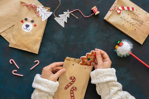 Vue de dessus des mains mettant des friandises à l'intérieur des sacs-cadeaux de Noël