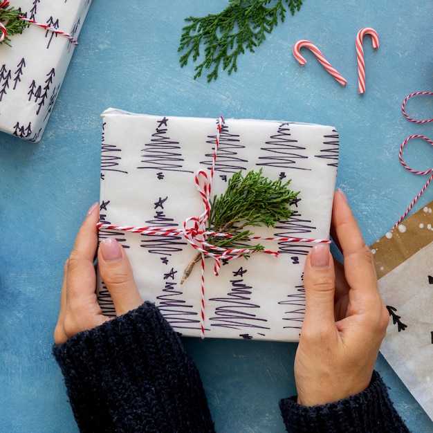 Vue de dessus des mains tenant un cadeau de Noël emballé