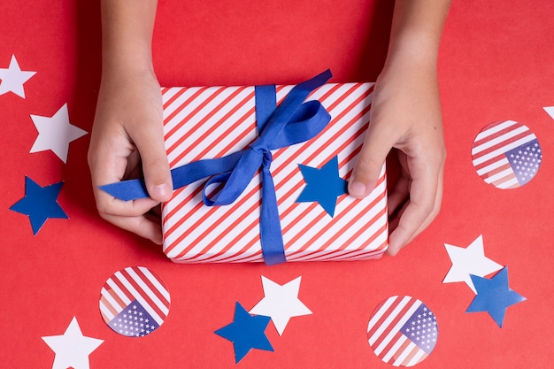 Photo gratuite vue de dessus mains tenant le drapeau des usa cadeau enveloppé avec décoration