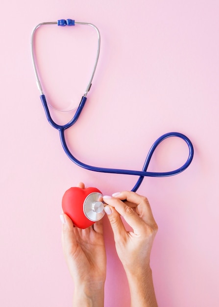 Vue de dessus des mains vérifiant le coeur avec stéthoscope