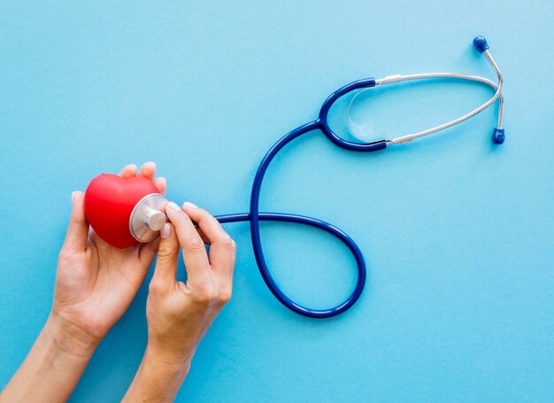 Vue de dessus des mains vérifiant la forme du coeur avec un stéthoscope