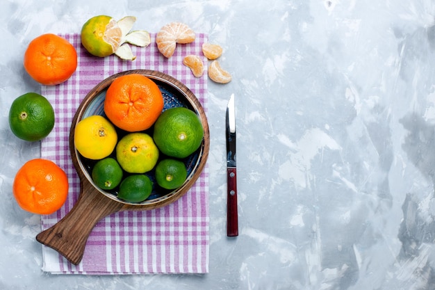 Photo gratuite vue de dessus des mandarines fraîches aigres avec des citrons sur une surface blanche claire