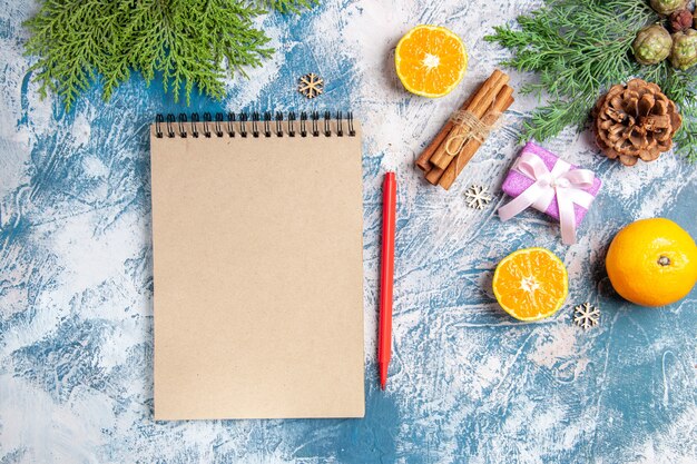 Vue de dessus des mandarines fraîches avec bloc-notes et cadeaux sur fond bleu