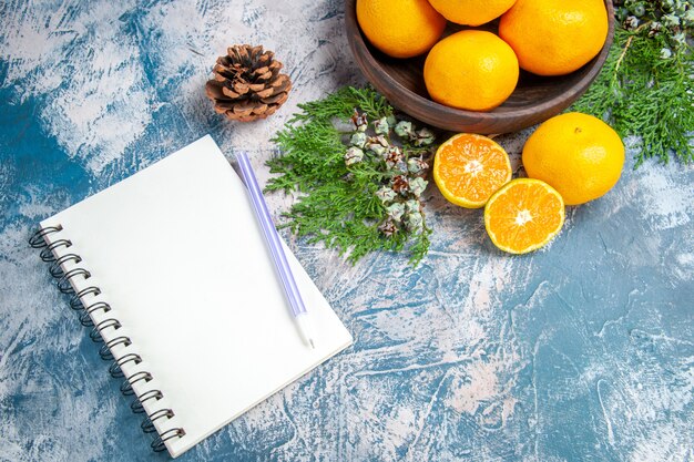 Photo gratuite vue de dessus des mandarines fraîches avec bloc-notes sur fond bleu clair