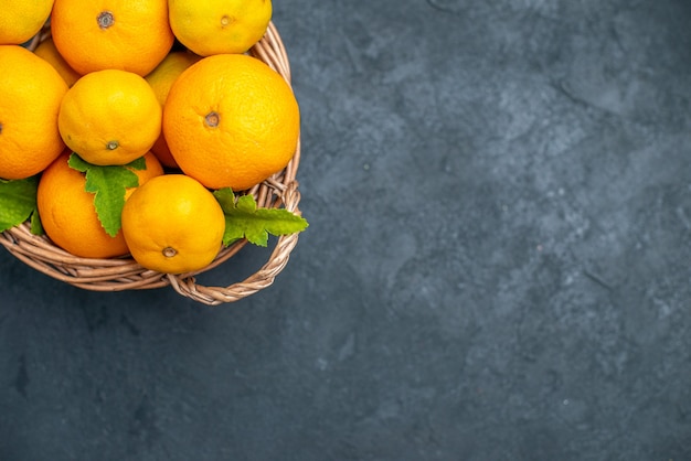 Vue de dessus des mandarines fraîches dans un panier en osier sur fond sombre