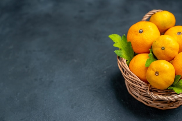 Vue de dessus des mandarines fraîches dans un panier en osier sur fond sombre