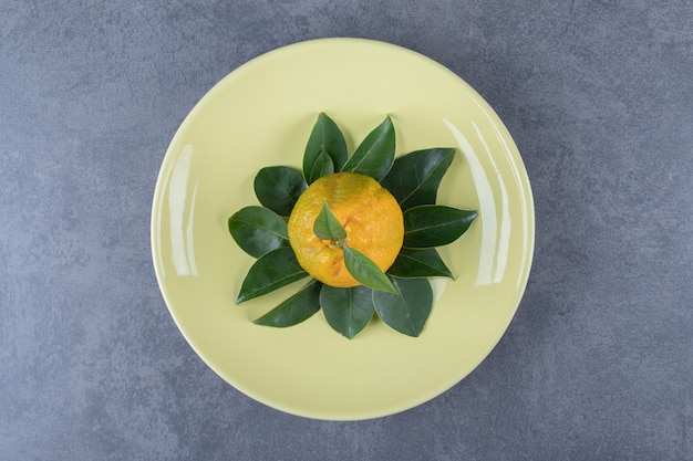 Photo gratuite vue de dessus des mandarines fraîches avec des feuilles sur une plaque jaune.