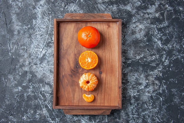 Photo gratuite vue de dessus mandarines fraîches mandarines pelées sur plateau en bois sur fond gris