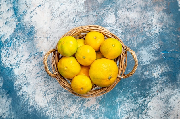 Vue de dessus mandarines fraîches sur panier en osier sur l'espace de copie de surface blanc bleu