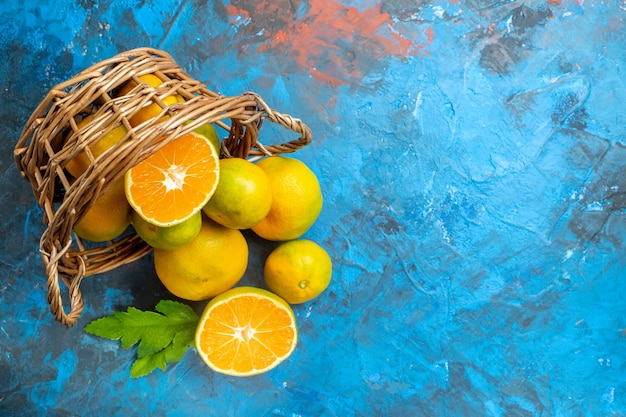 Photo gratuite vue de dessus des mandarines fraîches sur panier en osier sur l'espace libre de surface bleue