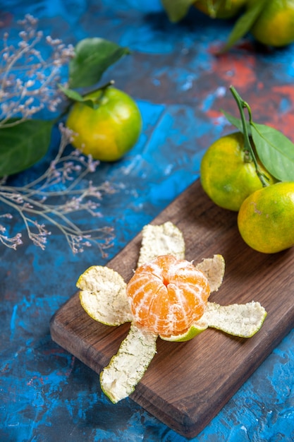 Vue de dessus mandarines fraîches pelées sur planche à découper sur surface bleue