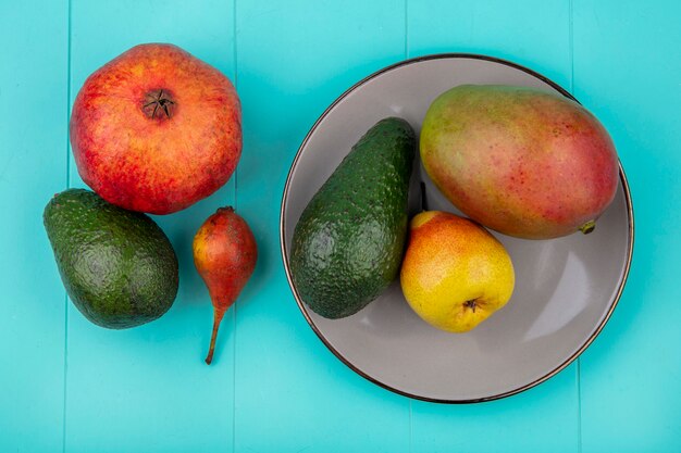 Vue de dessus de la mangue sur une assiette avec avocat poire sur surface bleue