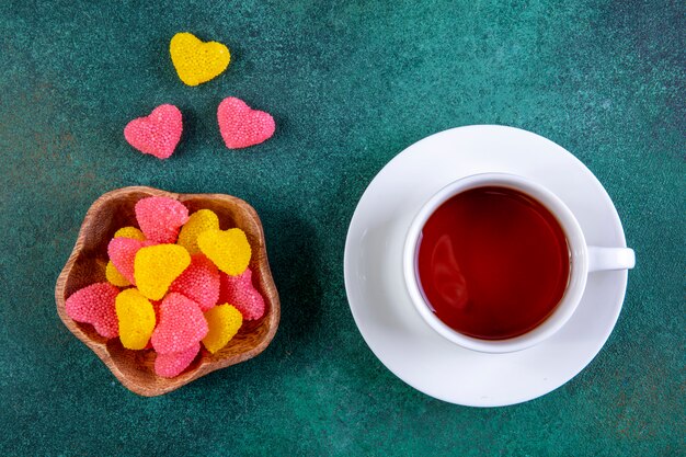 Vue de dessus marmelade colorée en forme de coeur avec une tasse de thé sur vert