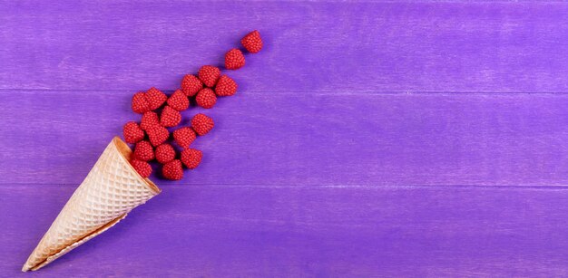 Vue de dessus de la marmelade de framboises avec un cornet gaufré sur fond violet