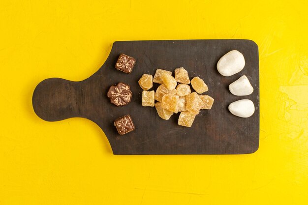 Vue de dessus de la marmelade en tranches sucrées et des confitures en tranches de sucre avec du chocolat sur une surface jaune