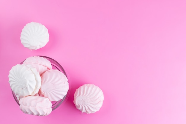 Une vue de dessus des meringues blanches à l'intérieur d'un bol en verre rond sur rose