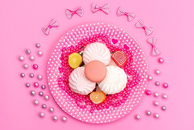 Une vue de dessus meringues et marmelades à l'intérieur de rose, plaque avec des arcs sur rose, confiserie de bonbons gâteau