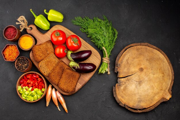 Vue de dessus des miches de pain noir avec assaisonnements tomates et aubergines sur fond sombre salade santé repas mûr