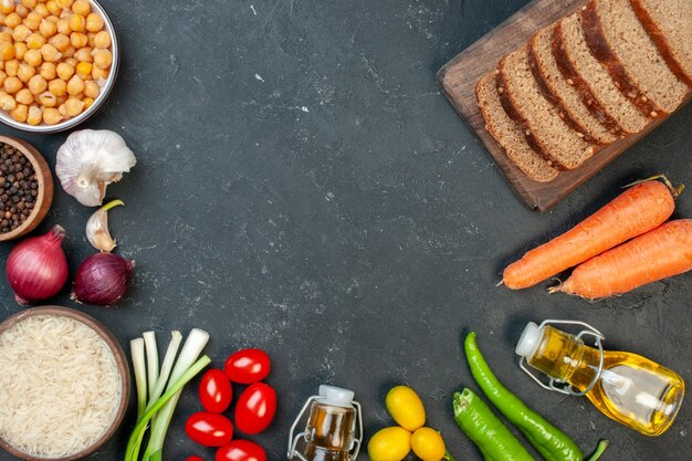 Vue de dessus des miches de pain noir avec des légumes sur fond gris foncé